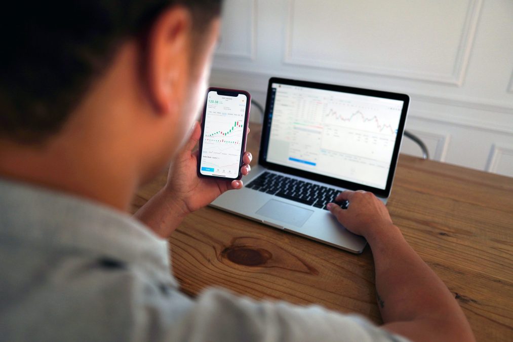 estate agent looking at his phone and laptop at a report detailing reaching their goals