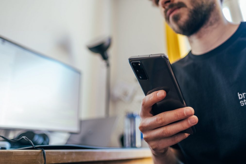 man on his phone about to leave a review for an estate agent