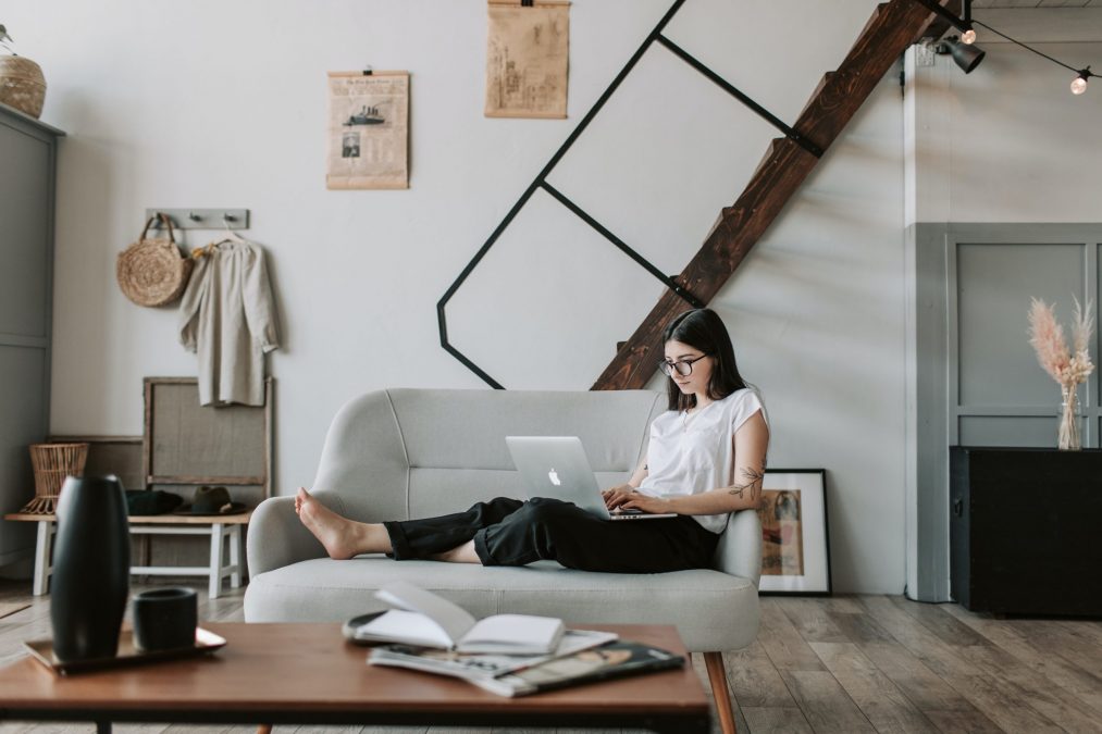 lady sitting on a grey sofa with her laptop