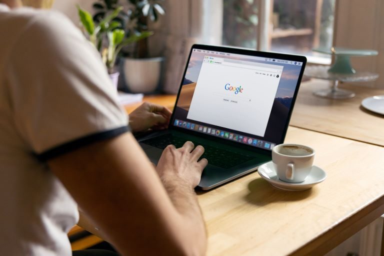 Person at table with a laptop, searching on Google